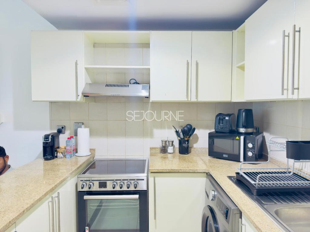 a kitchen with white cabinets and a stove top oven at DA86 - Well Design Studio in Dubai Arch tower in Dubai