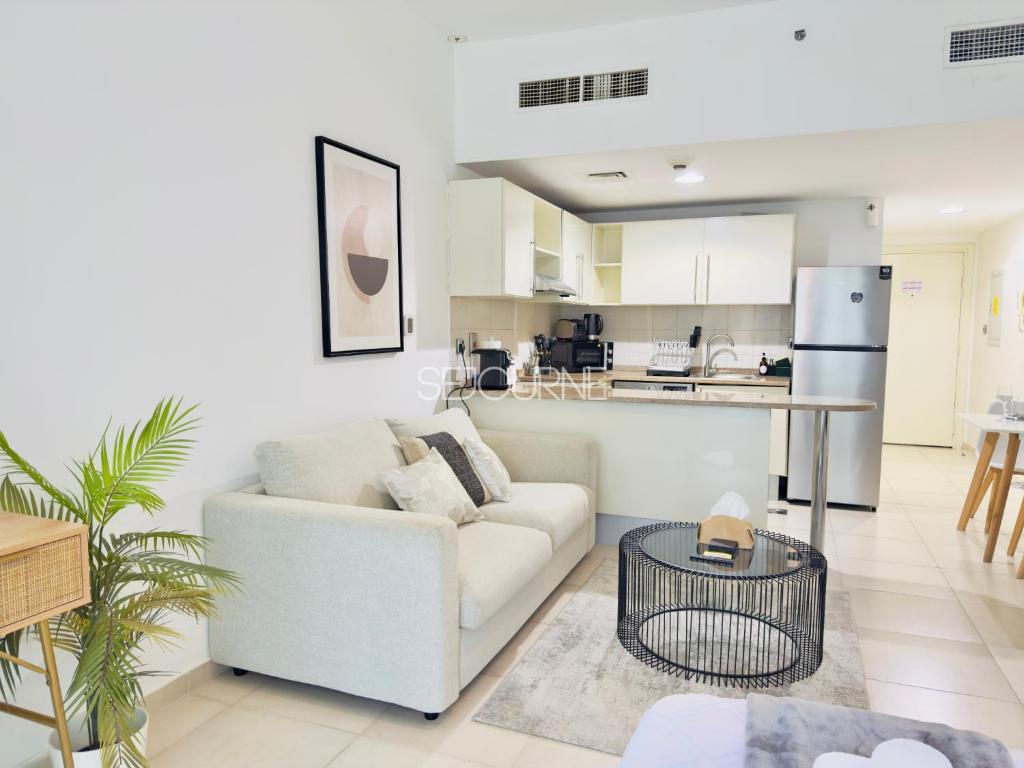 a living room with a white couch and a kitchen at DA86 - Well Design Studio in Dubai Arch tower in Dubai
