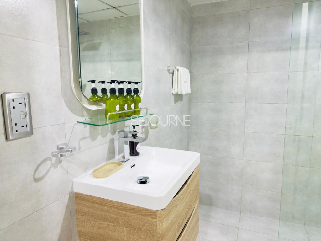 a bathroom with a white sink and a mirror at DA86 - Well Design Studio in Dubai Arch tower in Dubai