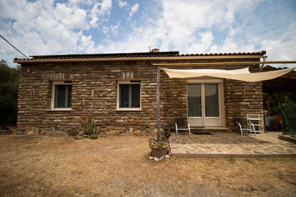 Una casa de ladrillo con una sombrilla delante de ella. en Au Pont De Tuarelli, Ludique, Fango, en Manso