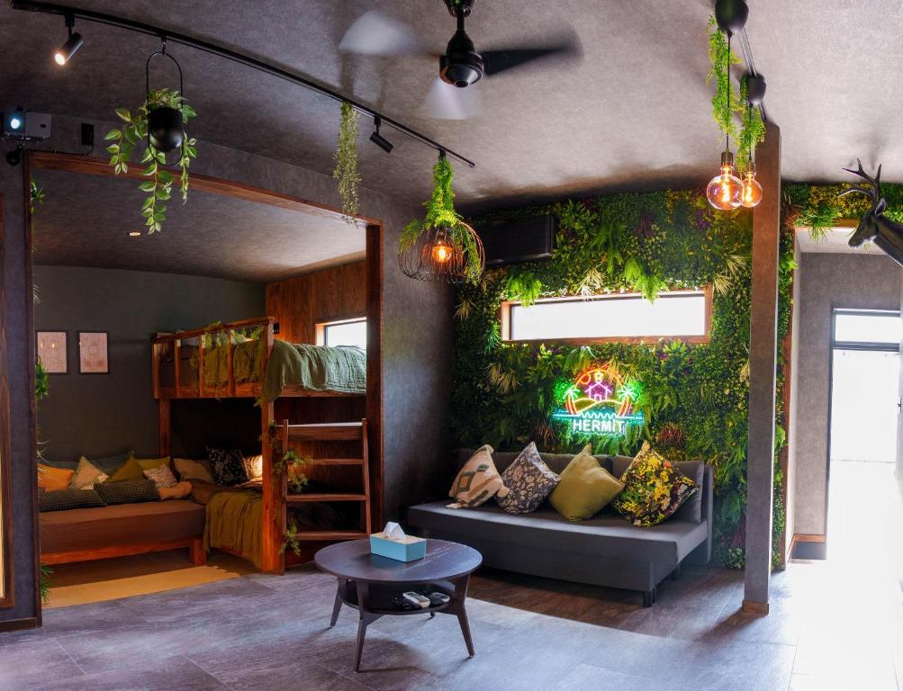 a room with a green wall with a couch and a table at 100度越えサウナ,森林浴,絶景パノラマビュー,森の中の隠れ家,星見ジャグジー---ハーミットたいとう--- in Shiigi