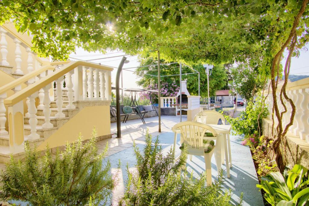 a patio with a staircase and chairs and plants at Olea House in Lukoran