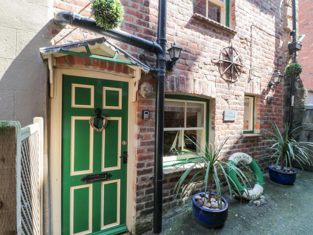 a green door on a brick building with potted plants at The Old Cottage in Staithes