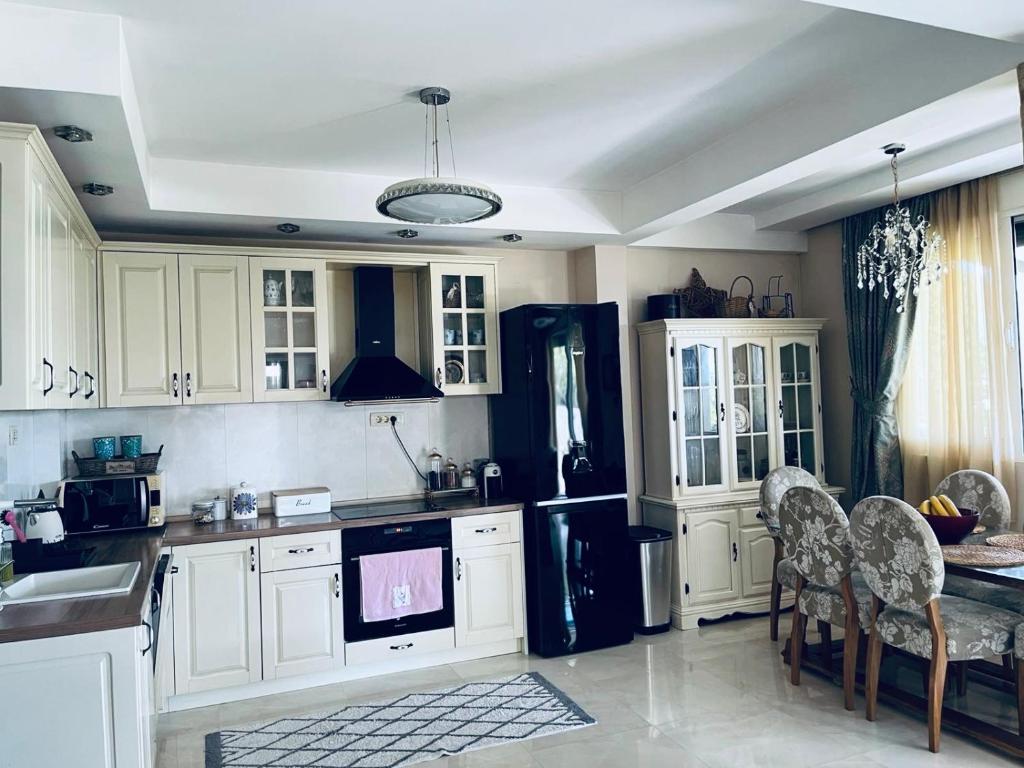 a kitchen with white cabinets and a black refrigerator at Apartman Maja in Herceg-Novi