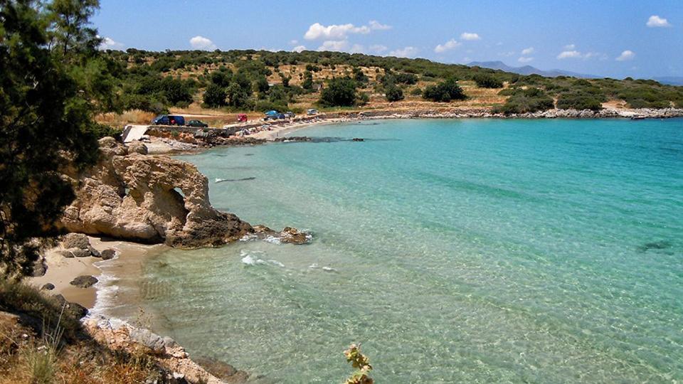 a beach with blue water and a group of people at Chrisambelos Apartments in Istro