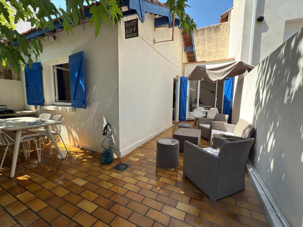 un patio avec des chaises et une table dans un bâtiment dans l'établissement Valras-Loc - Maison de Pecheur, à Valras-Plage