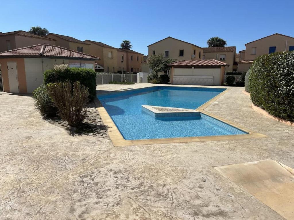 - une piscine dans une cour avec des maisons dans l'établissement Valras-Loc Maison T3, à Valras-Plage