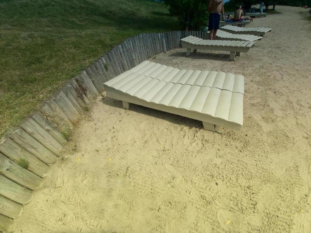 a white bench sitting in the sand next to a fence at Light House in Vilnius