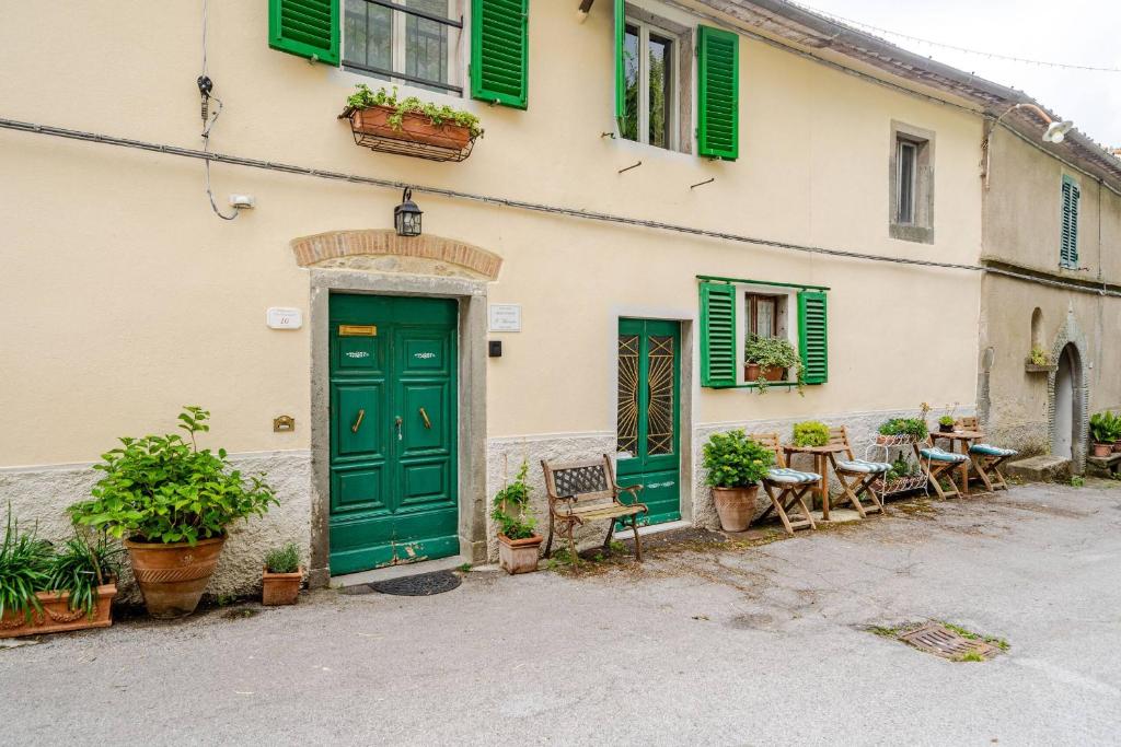 a building with green doors and tables and chairs at Antica Dimora Il Murrotto in Lanciole