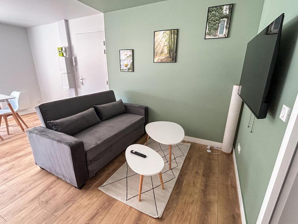 una sala de estar con un sofá y una mesa en L'Échappée Verte - appartement 1 chambre, en Saint-Méloir-des-Ondes