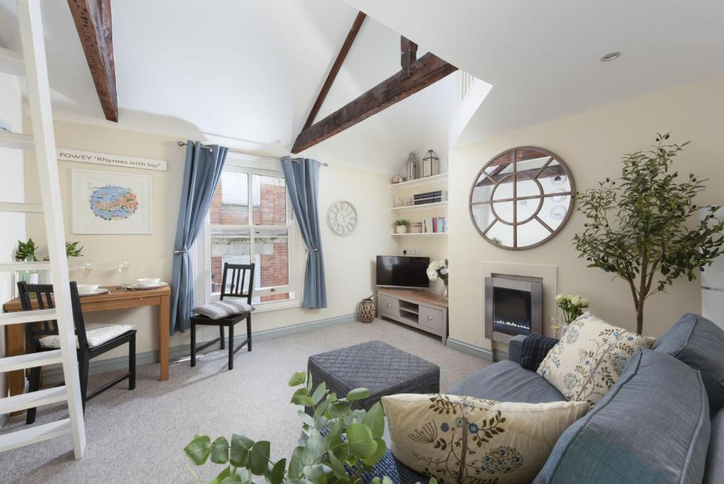 ein Wohnzimmer mit einem blauen Sofa und einem Schreibtisch in der Unterkunft Bessie Ellens Cottage in Fowey