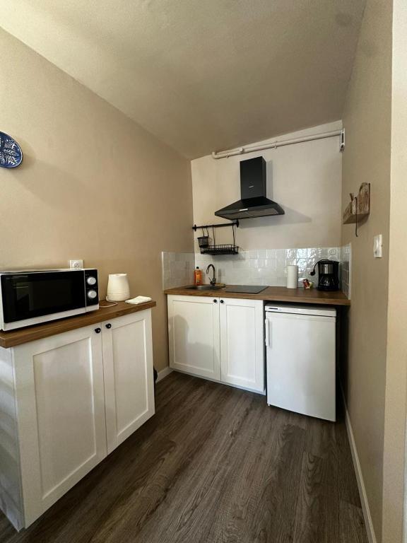 a small kitchen with white cabinets and a microwave at Studio 4 Aux volets bleus in Aulus-les-Bains