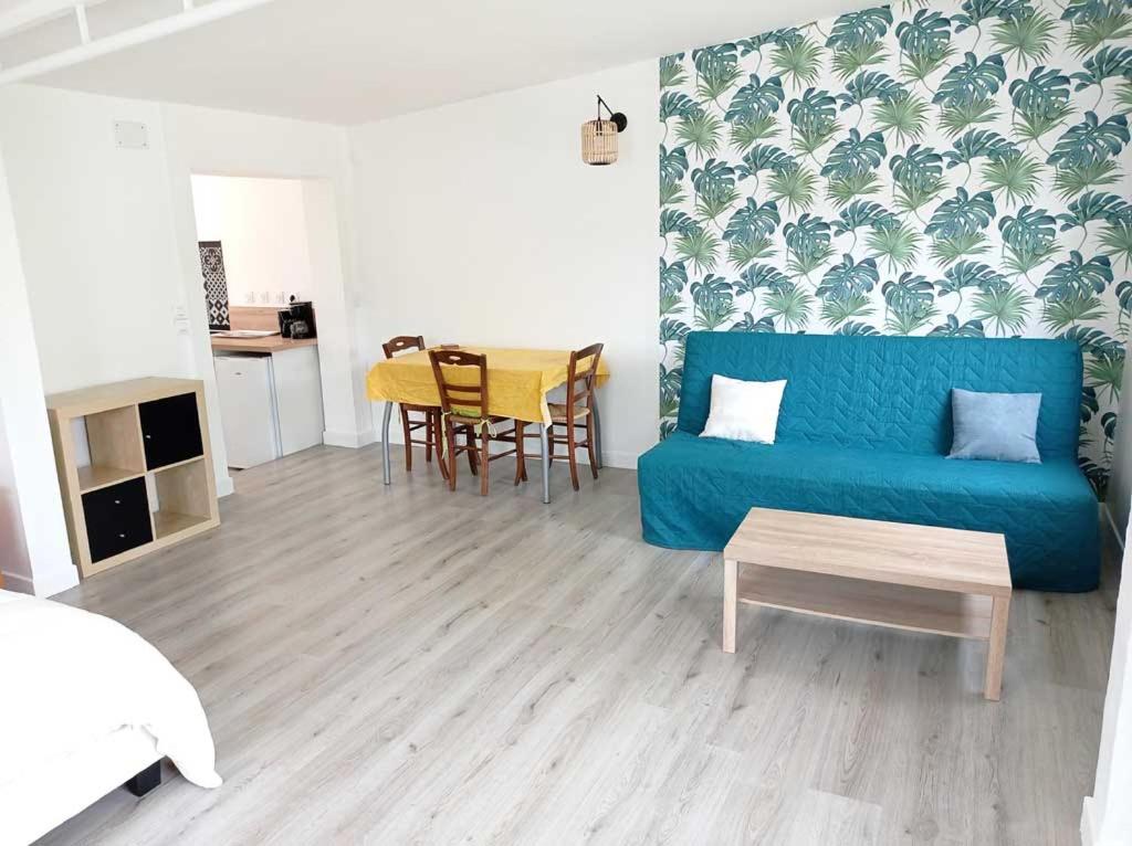 ein Wohnzimmer mit einem blauen Sofa und einem Tisch in der Unterkunft Nid du Merle, Pessac in Pessac