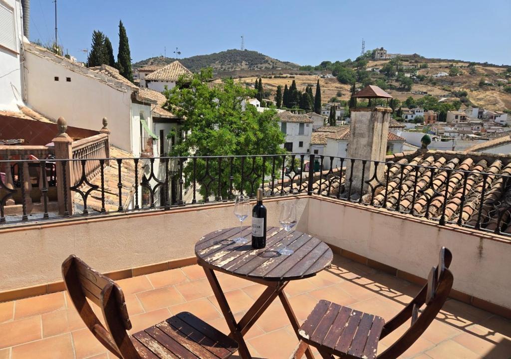 - Balcón con mesa y sillas y botella de vino en El Balcón del Albaicín, en Granada
