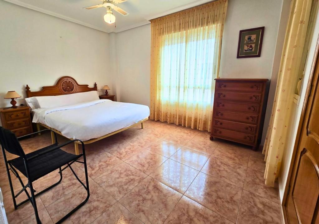Un dormitorio con una cama, una silla y una ventana en Apartamento Las Olas Santa Pola, en Santa Pola
