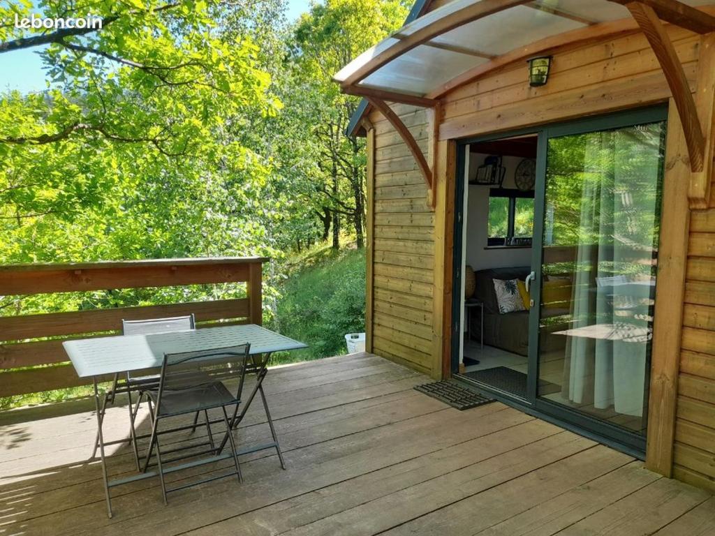 une terrasse en bois avec une table et des chaises dans une cabine dans l'établissement Mon chalet au cœur des Cévennes, à Vébron