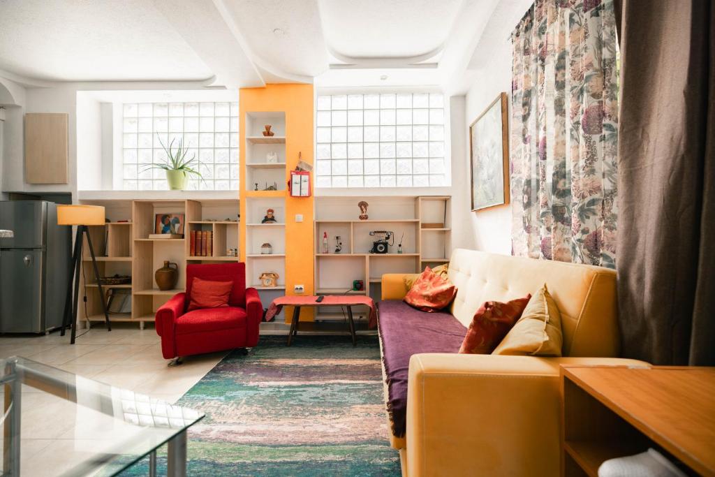 a living room with a yellow couch and a red chair at Easy Stay Apartments in Pristina
