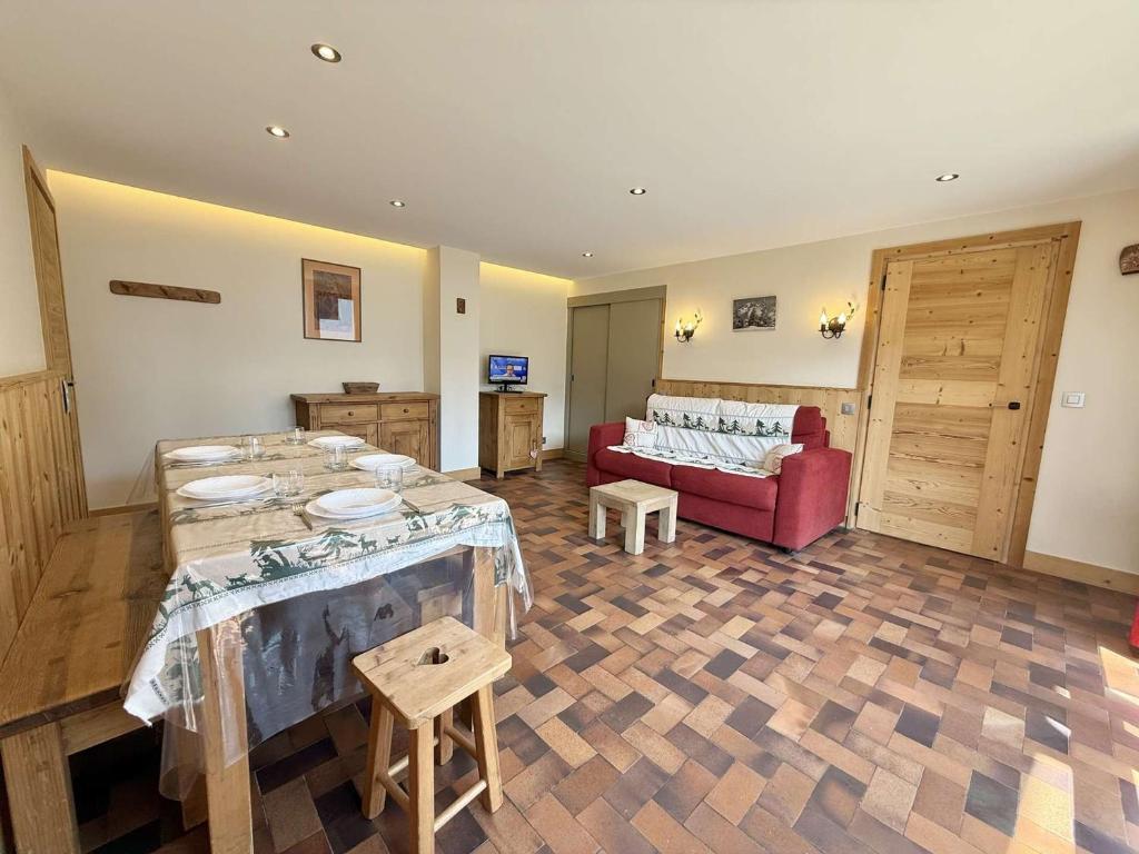 a living room with a table and a red couch at Appartement cosy au cœur de Praz-Sur-Arly - 5 pers, proche centre et pistes, parking et casier ski - FR-1-603-35 in Praz-sur-Arly