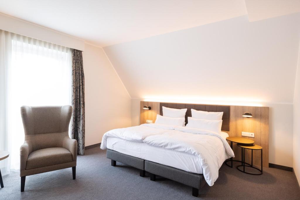 una habitación de hotel con una cama y una silla en Stadthotel Dinklage, Self-Check In, Restaurant am Hotel, en Dinklage