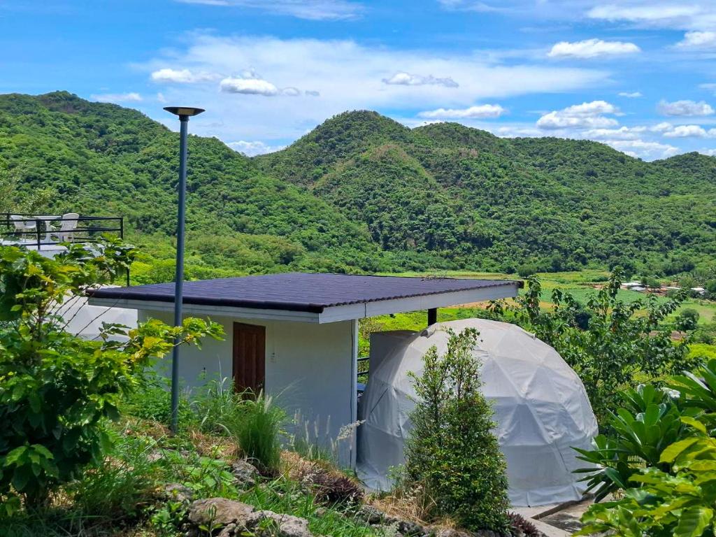 a small white house with a gazebo in front of mountains at Tawanja Resort in Ban Mai