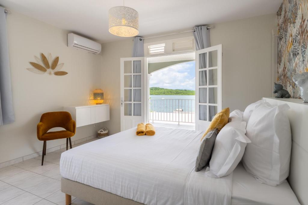 Una habitación blanca con una cama y una ventana en Bel Embrun - Villa Iléenne, en Les Trois-Îlets