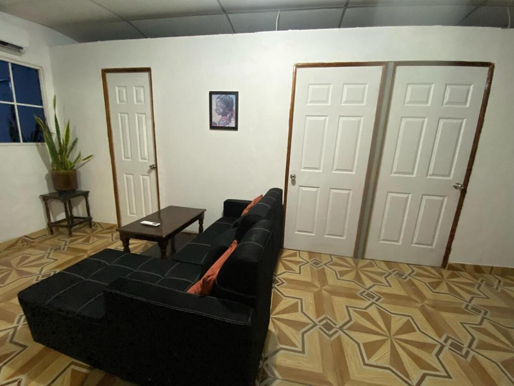 a living room with a black couch and two doors at Aguiñada's house en el Rosario La Paz in El Rosario