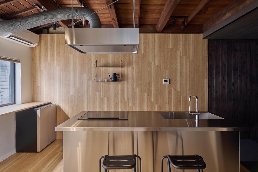 a kitchen with a sink and a counter with stools at Alchemy 0 in Osaka