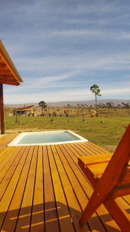 eine Holzterrasse mit einem Pool auf einem Feld in der Unterkunft La agreste in Villa Yacanto