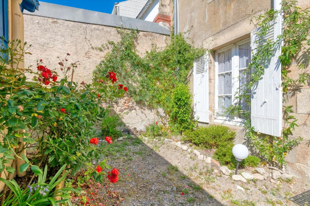 un jardín con flores rojas junto a un edificio en Nid Douillet Entre Plage Et Port, en Le Pouliguen