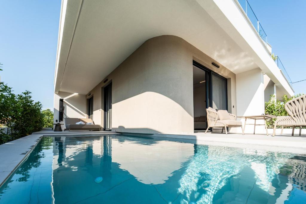 a villa with a swimming pool and a house at Haven Luxury Living in Keramoti