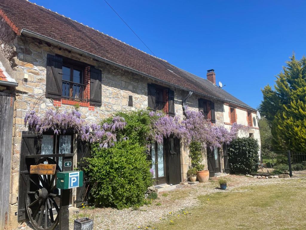 a building with purple wisterias on the side of it at Les Gites de Montinazeau - 3 adjoining gites set in quiet and beautiful countryside with free Wi-Fi in Chéniers