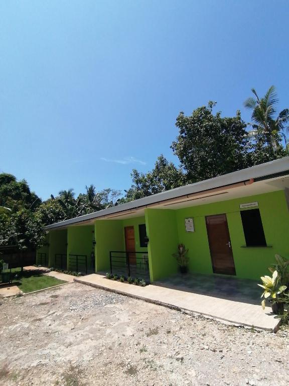 a green building with brown doors on it at Malunggay's Inn in Panglao Island