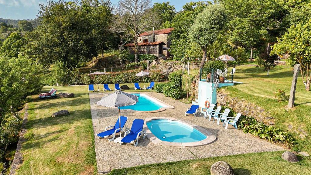 una piscina al aire libre con sillas y sombrilla en Quinta da Chanca, en Paredes de Coura