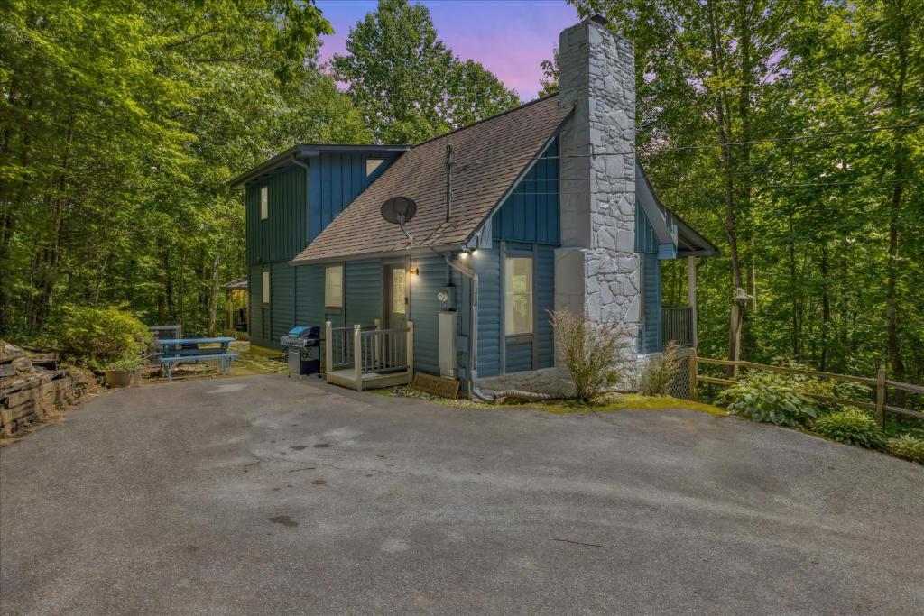 mały niebieski domek w środku lasu w obiekcie Cozy Timbers by Beyond Expectations w Hot Tub w mieście Rocky Grove