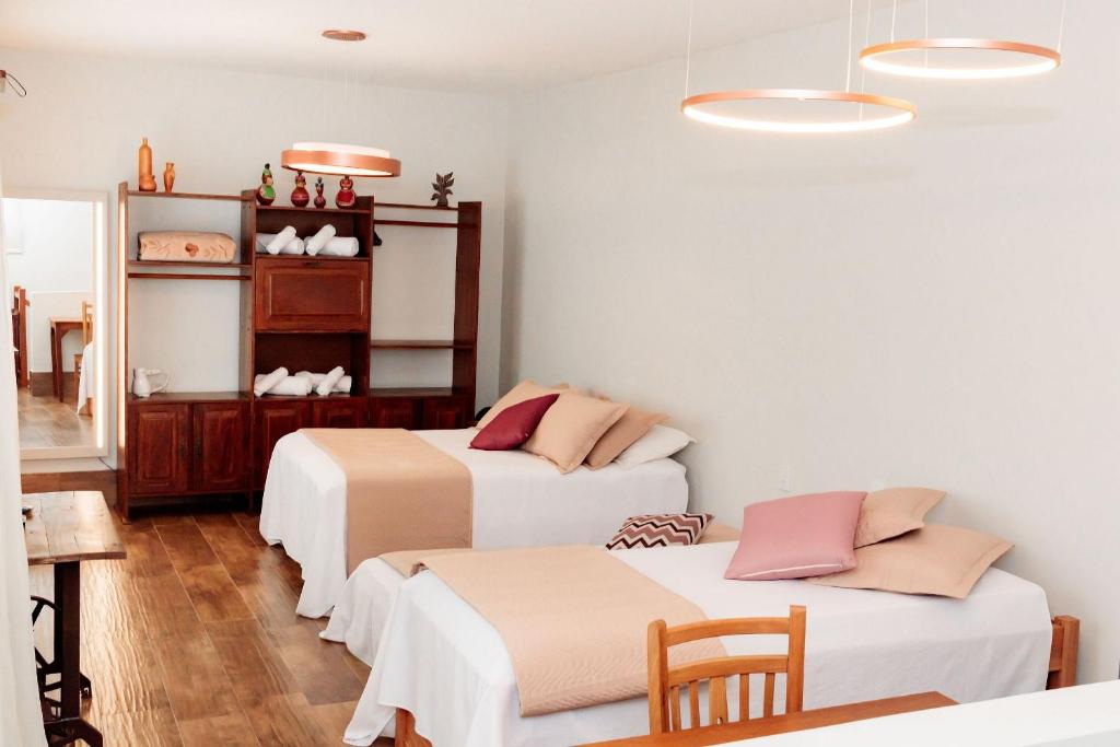 two beds in a room with white walls and wooden floors at Casa Duplex c/ suíte cozinha completa e ventilador in Diamantina