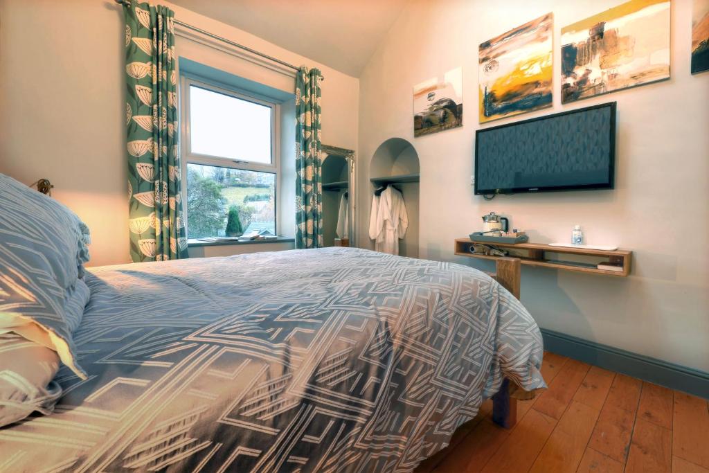 a bedroom with a bed and a flat screen tv at Little John Hotel in Hathersage
