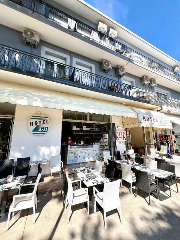 a restaurant with tables and chairs in front of a building at Hotel Zen in Lignano Sabbiadoro