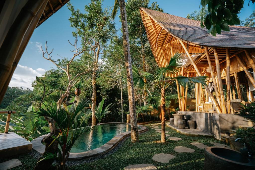 a resort with a swimming pool and trees at Umah Bali Kuno Villa New in Tampaksiring