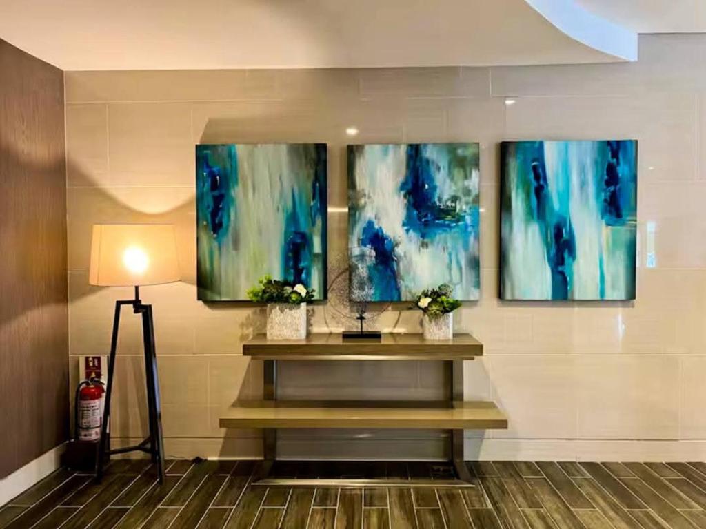 a lobby with three paintings on the wall and a table at SLY Staycation at Shore Residences Mall of Asia in Manila