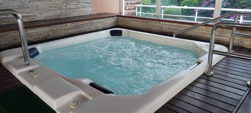 a jacuzzi tub in a room with a window at Gramado Village Apartamento no Centro in Gramado