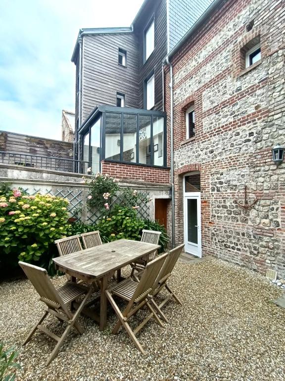 una mesa de madera y sillas frente a un edificio de ladrillo en Le Cinquante-Trois, en Saint-Valéry-en-Caux