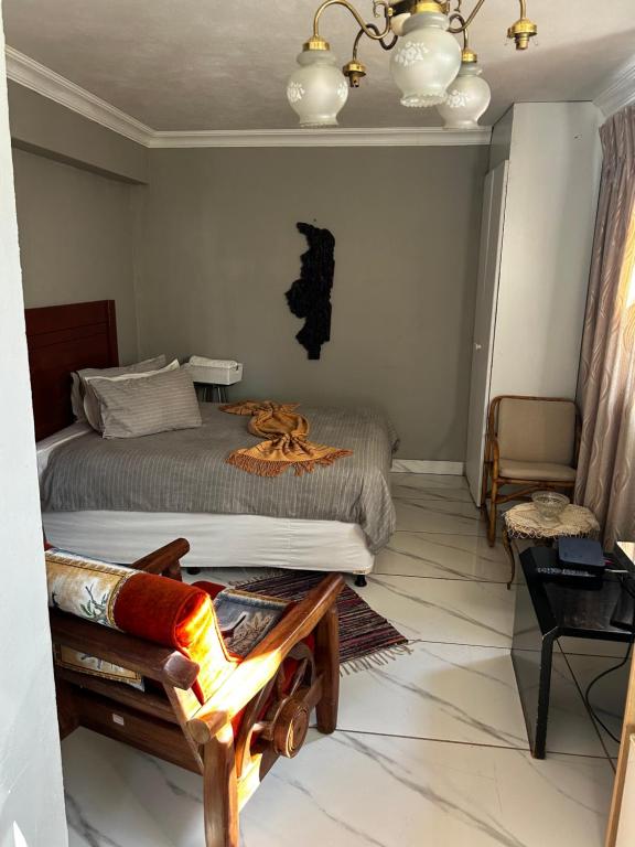 Un dormitorio con una cama y una silla dentro. en Garden Studio in Waterkloof Ridge, en Pretoria