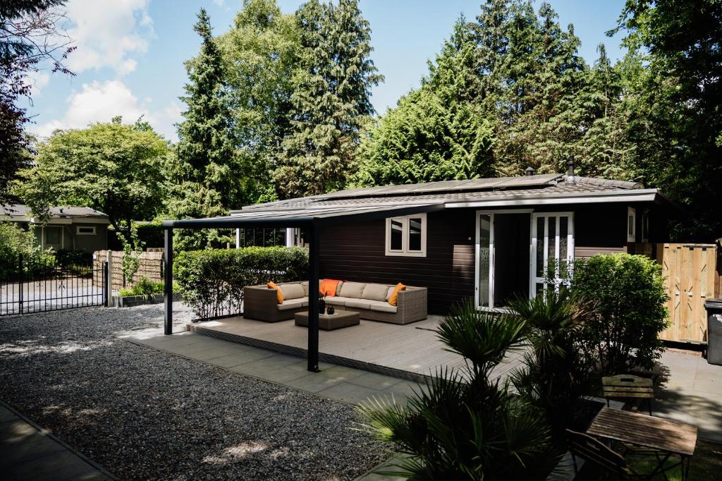 a tiny house with a porch and a couch at Veluwse Wellness Lodge Selina in Ermelo