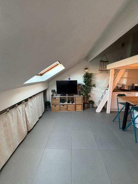 an attic room with a flat screen tv and a table at Cosy Rooftop Studio Nice Centre in Nice