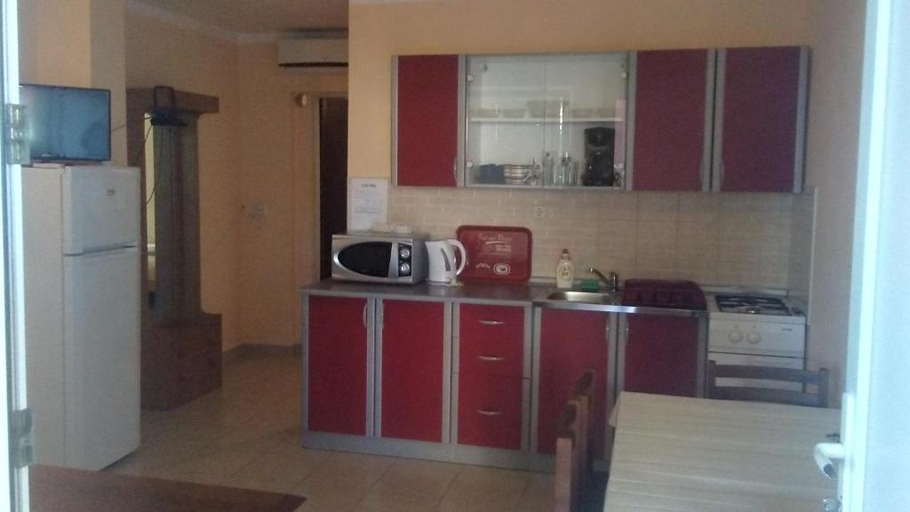a kitchen with red cabinets and a sink and a microwave at Apartmani Trputec, otok Vir in Vir