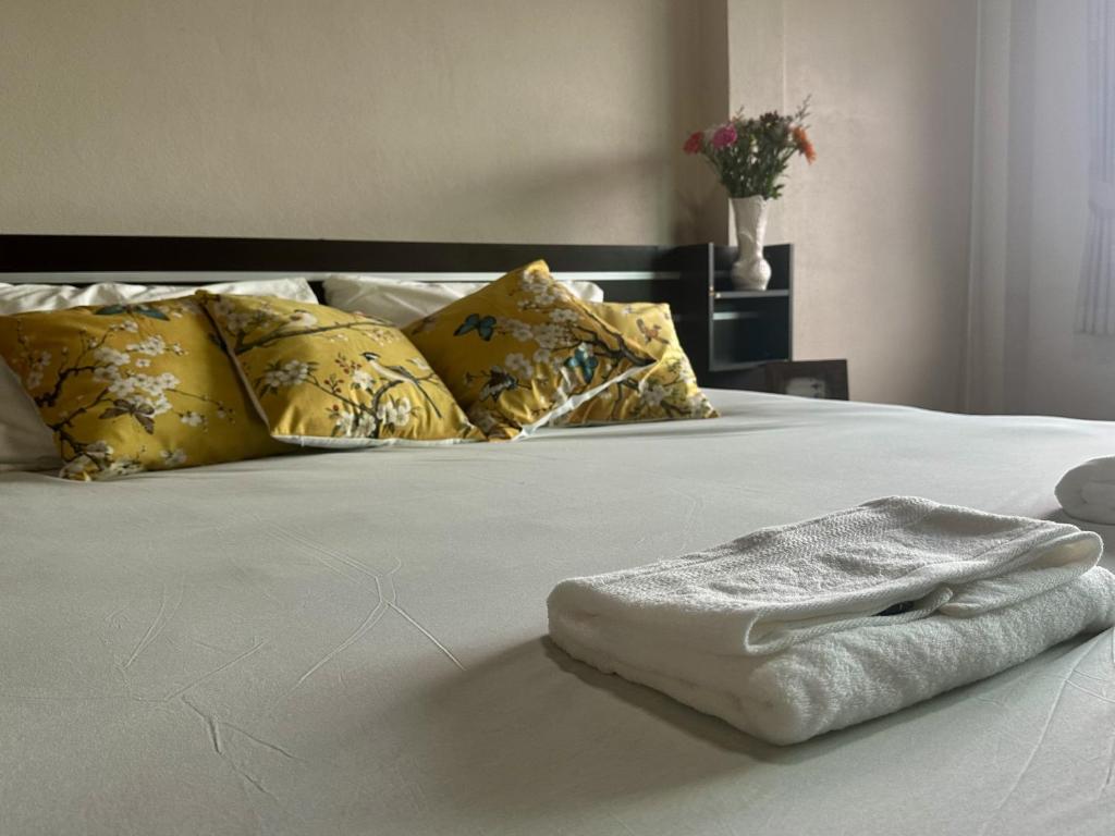 a white towel on a bed with yellow pillows at Yoga Bed and Breakfast in Chiang Mai