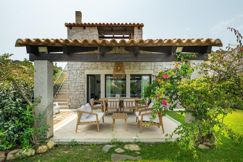 a patio with a table and chairs in a yard at Villa Bouganville Cala Sinzias in Castiadas