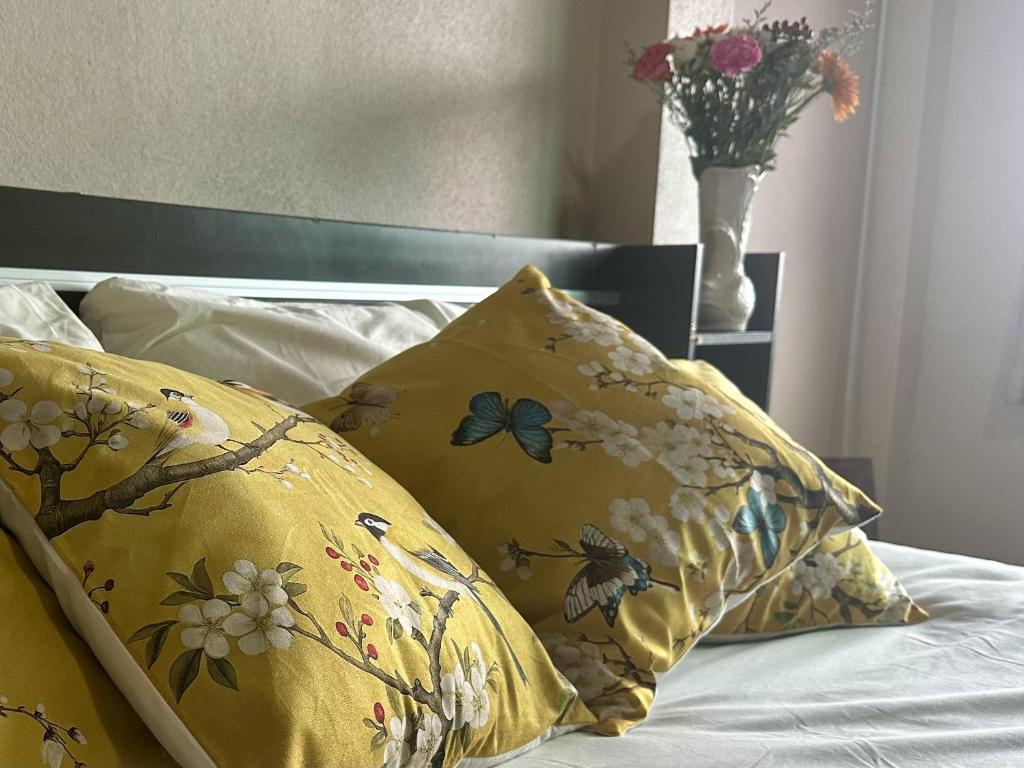 a bed with a yellow pillow with butterflies and a vase of flowers at Yoga Bed and Breakfast in Chiang Mai