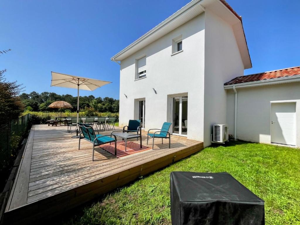 une terrasse en bois avec des chaises, une table et un parasol dans l'établissement Villa Climatisée 8 Pers, 4 chambres, 3 Sdb, à Saubion