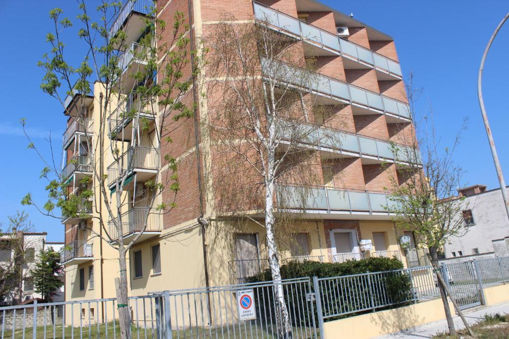 an apartment building with a fence in front of it at Scacchi 11 in Lido di Scacchi